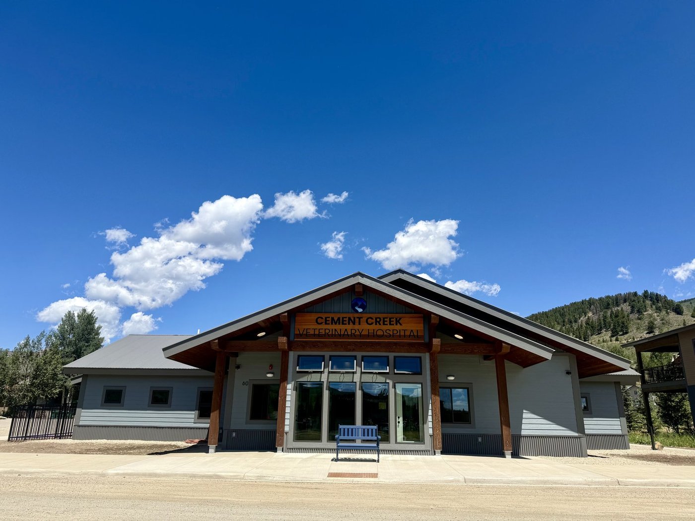 The Cement Creek Veterinary Hospital building under a blue sky, with the Gunnison Valley hillside behind it