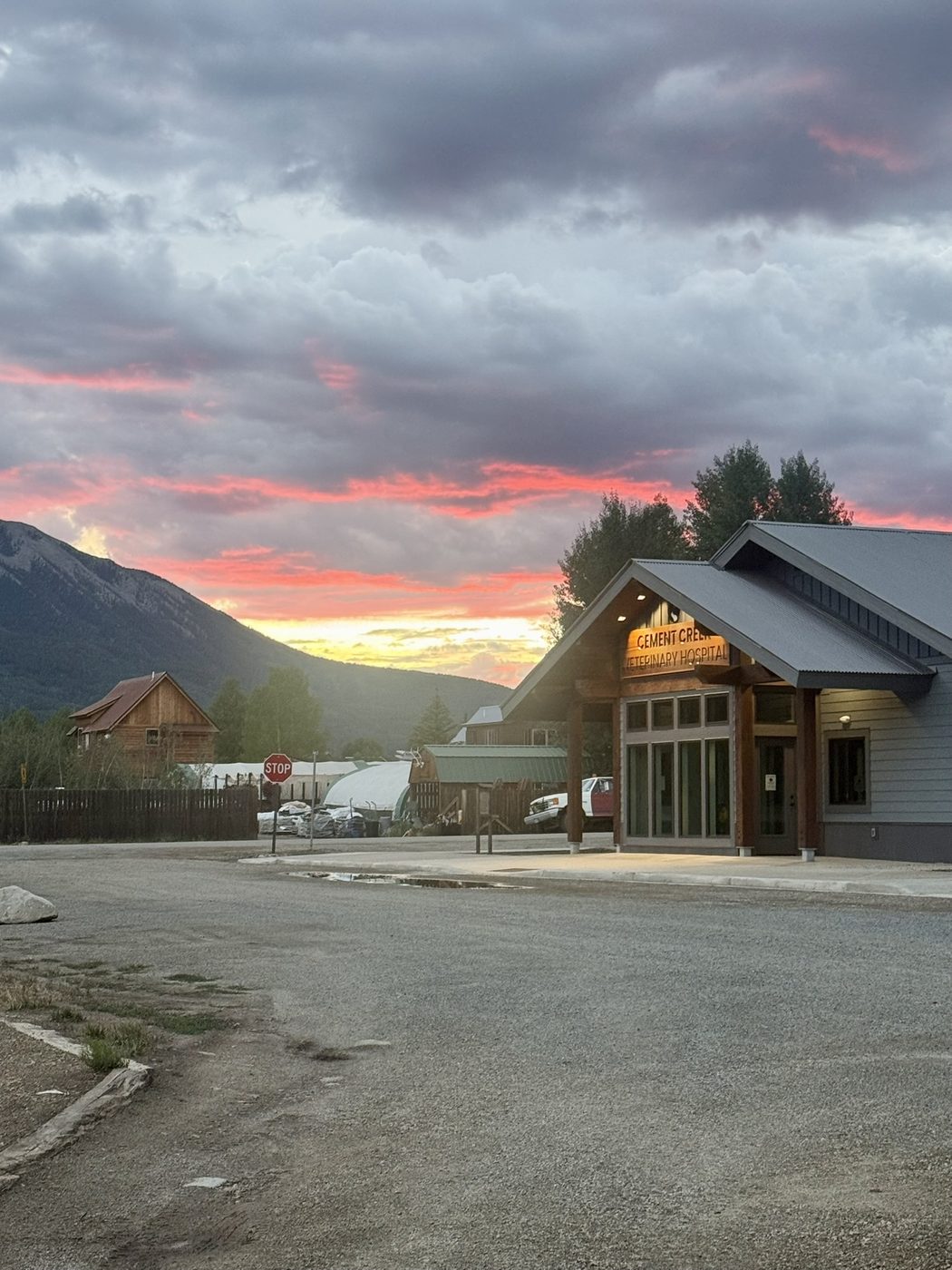 Sunset over Cement Creek Veterinary Hospital with the mountains behind and the sign lit