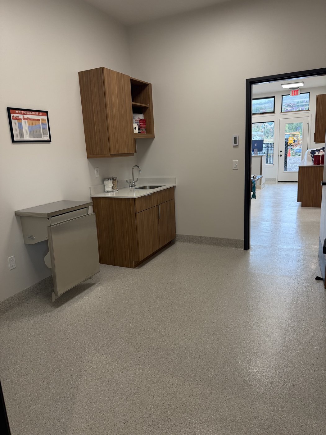 The finished exam room with wood cabinetry and a view down the hallway to the entrance