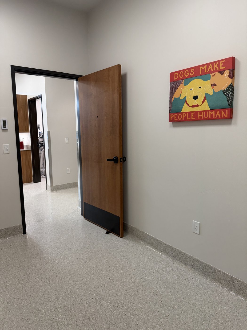 A hallway beside a colorful print reading “dogs make people human”