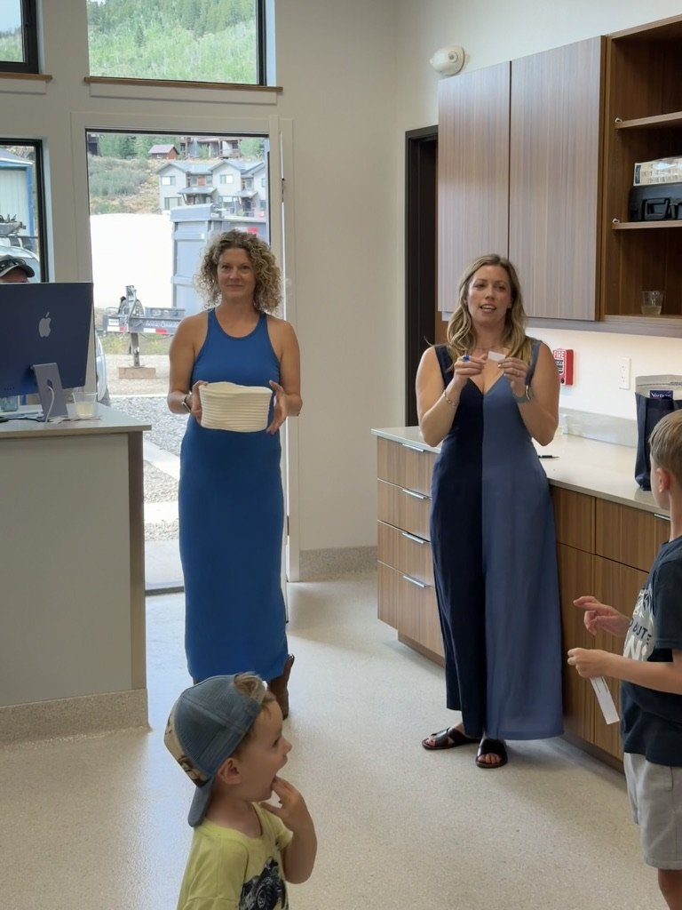 Two of the team showing something to a small crowd of guests and children