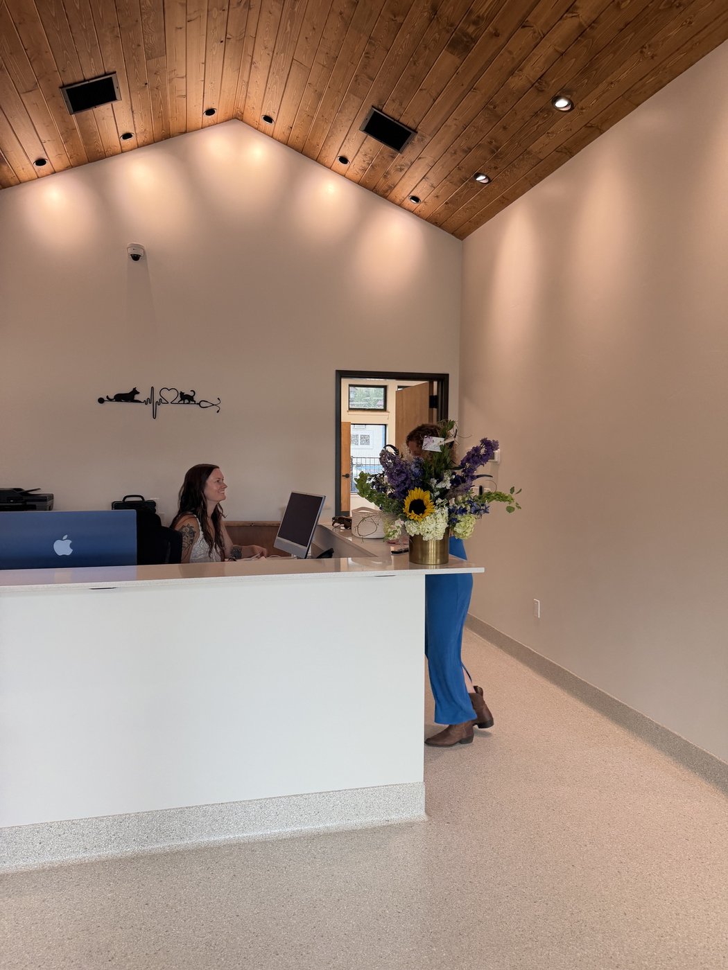 A team member at the front desk as a guest walks through the lobby