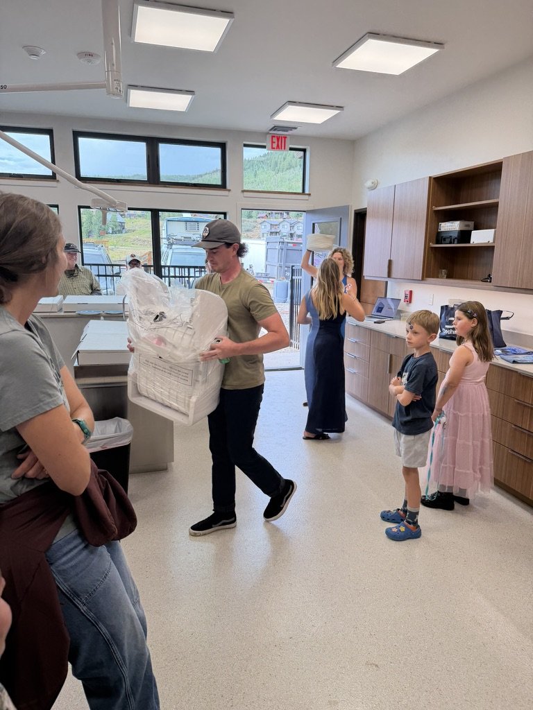 Carrying a wrapped raffle prize past guests and children in the treatment area