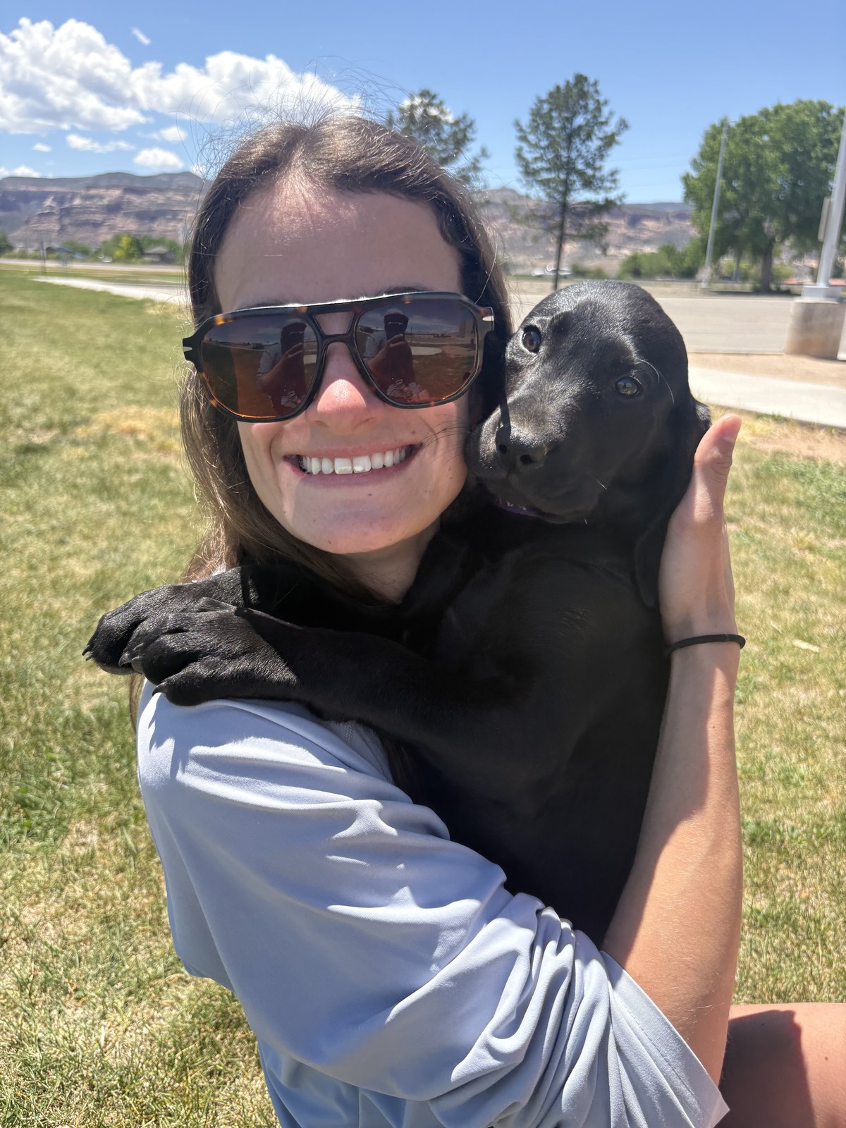 Hope Freeman, Veterinary Assistant at Cement Creek Veterinary Hospital, holding a black Labrador puppy